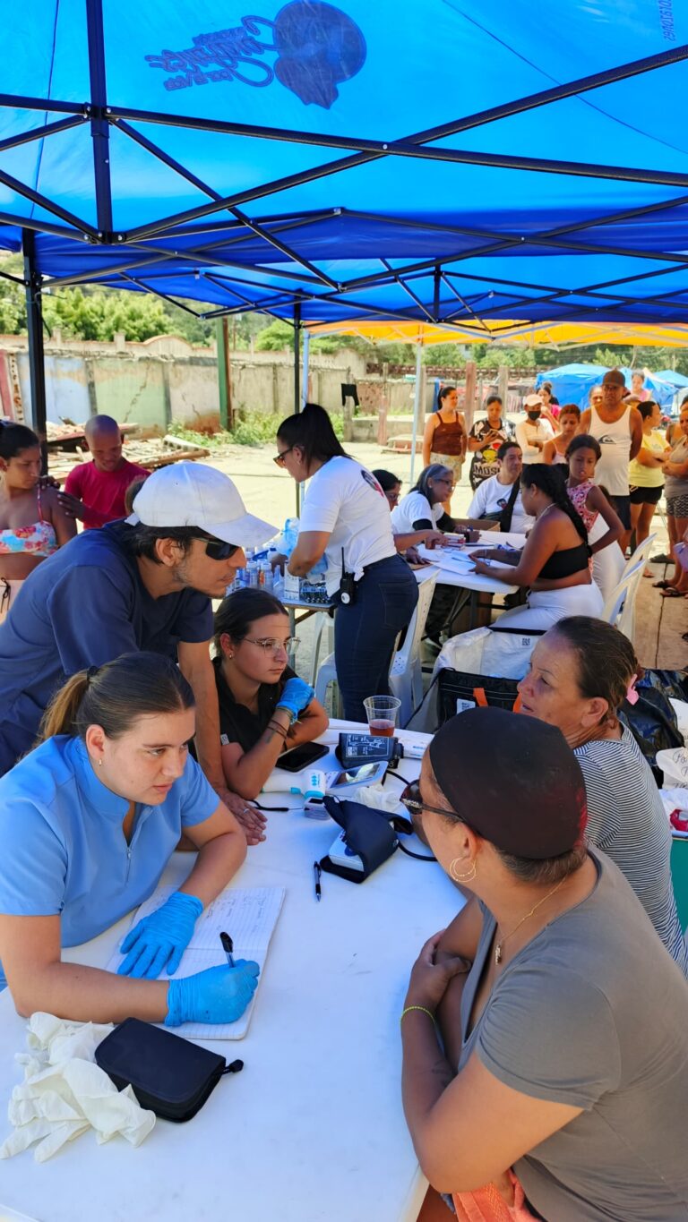 A medical professional speaks with community members under the outreach tents.