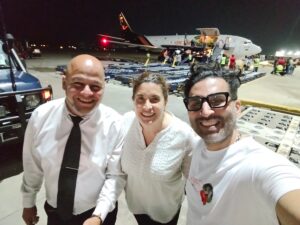 Members of the humanitarian operation stand beside an aircraft during the nighttime arrival