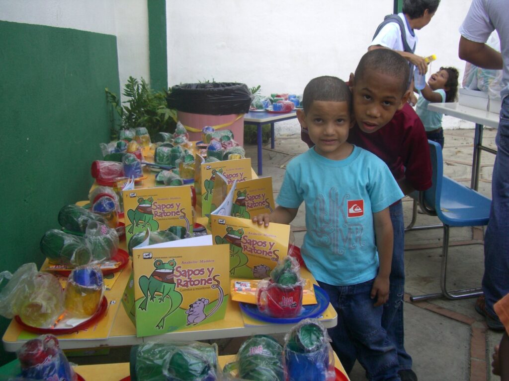 Children beside donated school supplies, food and gifts at Hogares Bambi Venezuela.