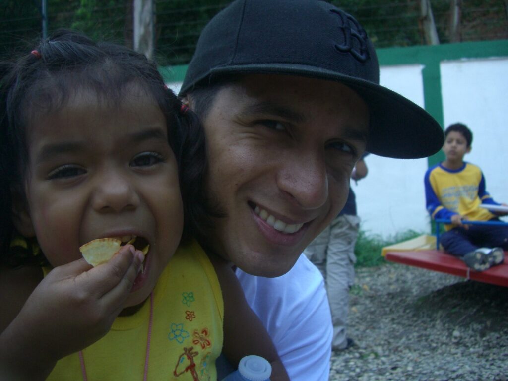 Román EL RO sharing a joyful moment with a child at Hogares Bambi Venezuela.