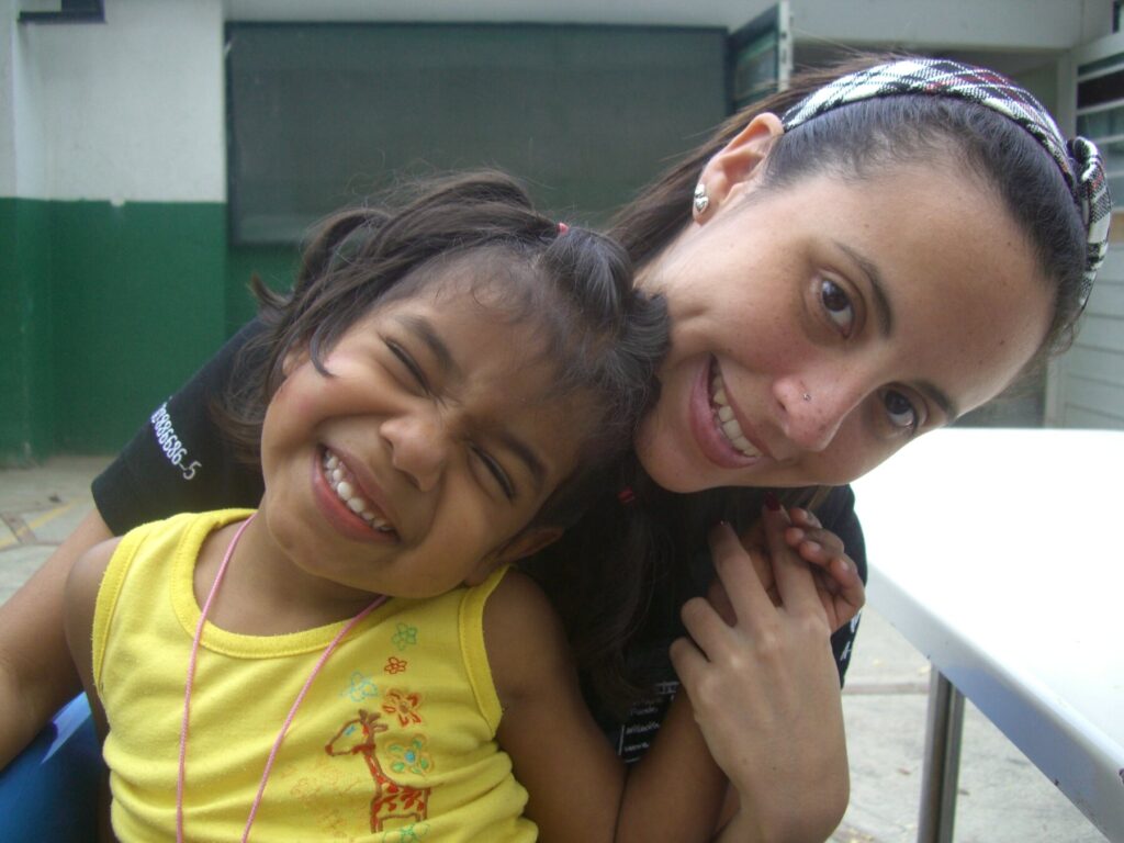 Hogares Bambi staff member smiling with a child during the Corazones por la Vida visit.