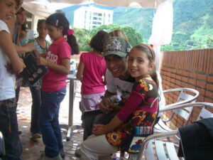 Román EL RO smiling beside a child during the 2011 Children’s Day gift activity with Soñar Despierto.