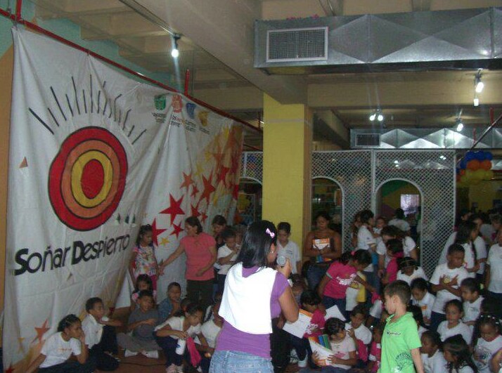 Children and volunteers participating in a Children’s Day activity beside a large Soñar Despierto banner.