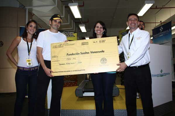 Participants presenting a Bs.F. 10,000 check to Fundación Sanitas Venezuela in Caracas.