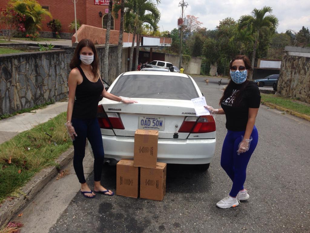 Two masked volunteers beside boxes prepared for a household delivery during the pandemic.