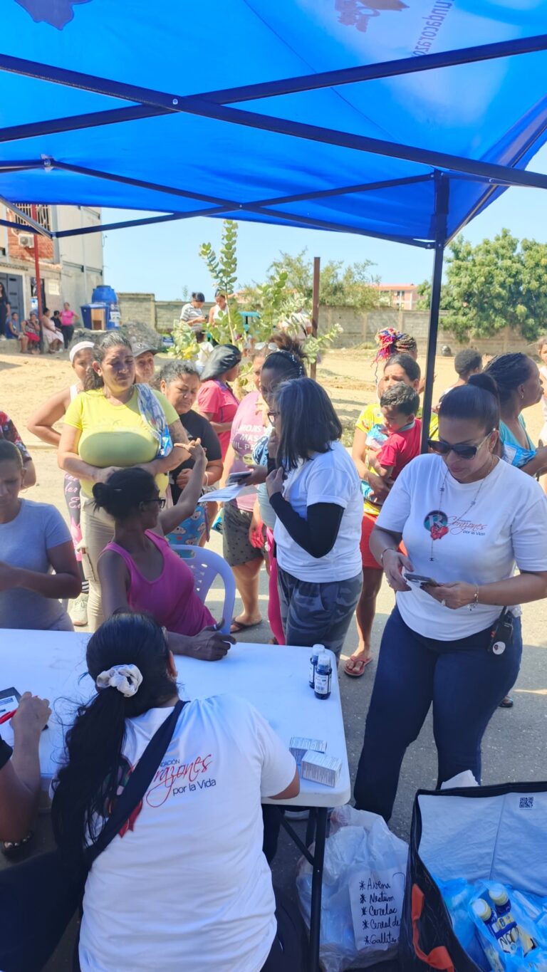 Foundation team and residents gathered beneath a blue canopy at the camp.